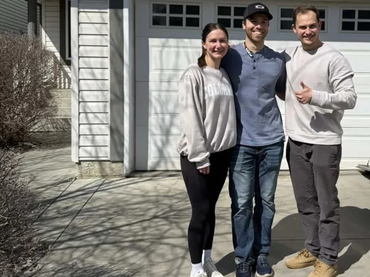Kurtlan U. and his girlfriend with Cameron in front of the garage