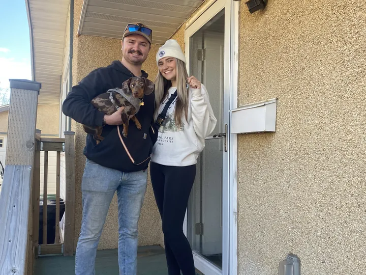 MacKenzie J. and Jordan at their front door with their dachshund, keys in hand